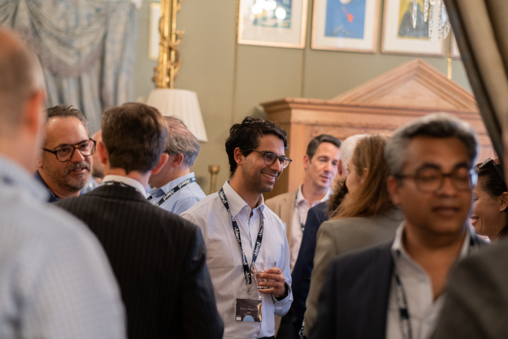 C-suite professionals engage in conversation at a Blend community networking event. They wear Blend lanyards.